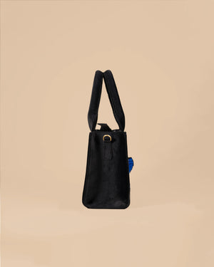Black handbag with a strap on a beige background