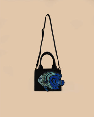 Black handbag with blue and green floral embroidery on a beige background