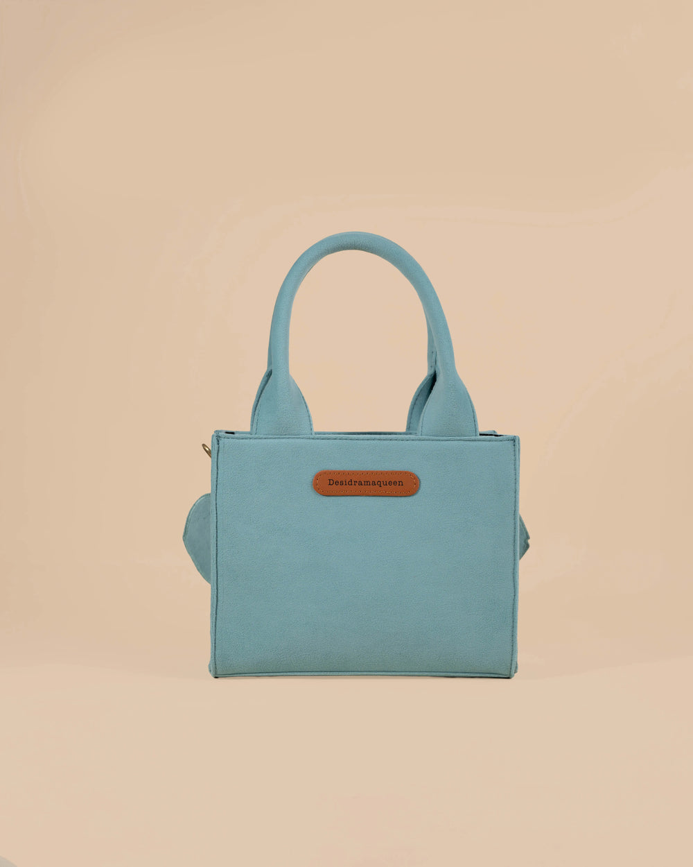 Blue handbag with pink fish designs on a beige background