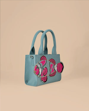 Light blue handbag with pink floral designs on a beige background