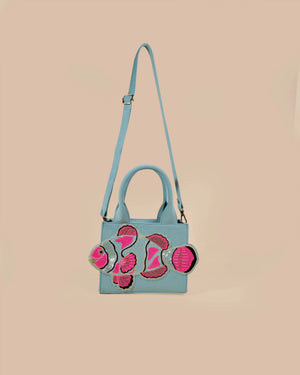 Light blue handbag with pink floral designs on a beige background