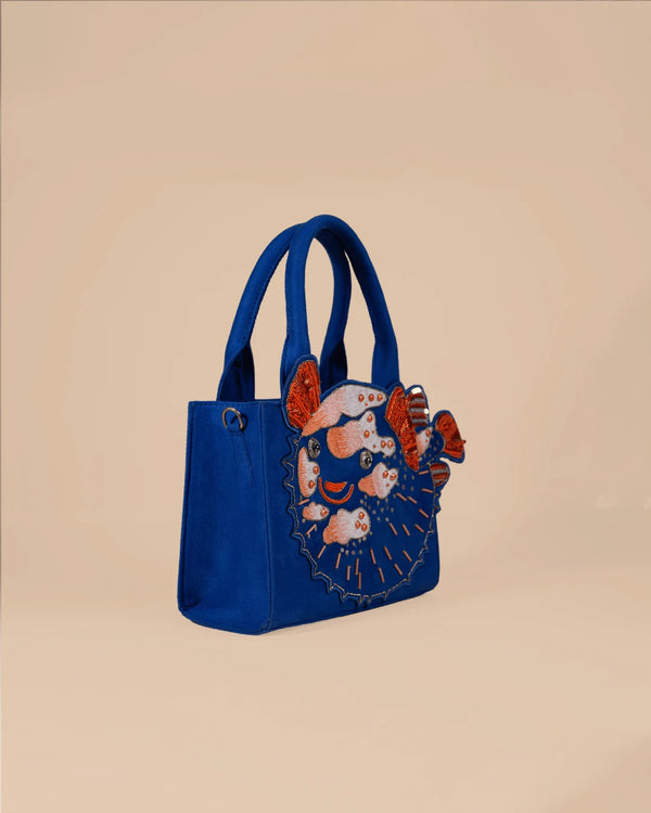 Blue handbag with decorative elements on a beige background