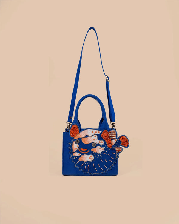 Blue handbag with embroidered design on a beige background