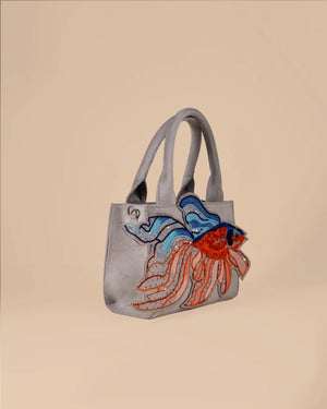 Gray handbag with a colorful fish design on a beige background