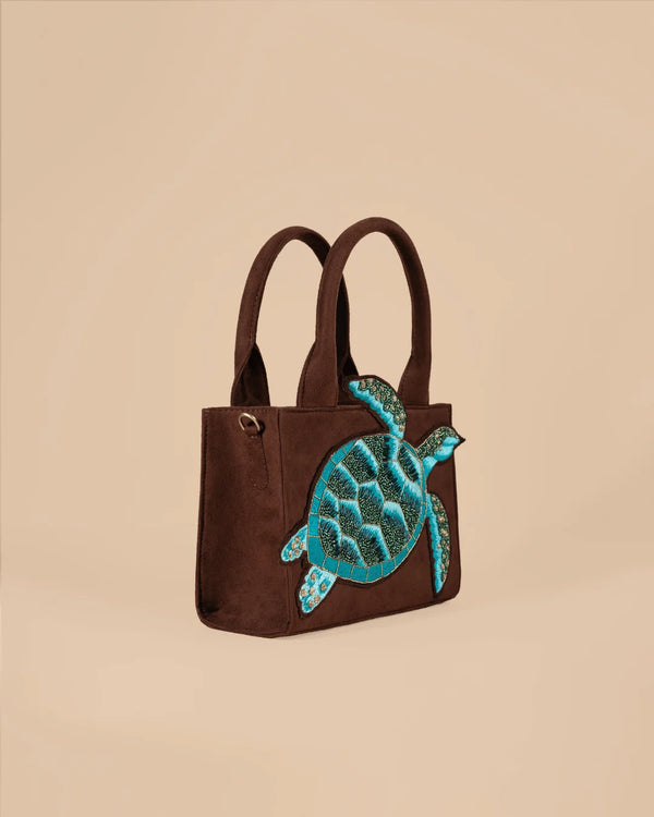 Brown handbag with a blue turtle design on a beige background