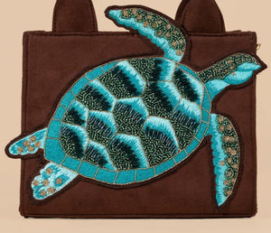 Brown bag with a large blue turtle patch on a beige background
