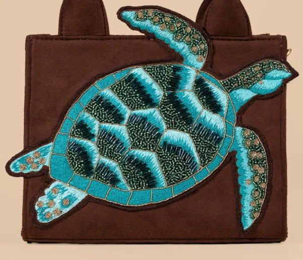Brown bag with a large blue turtle patch on a beige background
